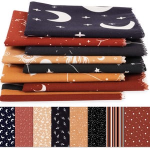 May include: A pile of fabric squares in assorted colours and celestial designs. The fabrics display moons, stars, and suns in white against navy, black, and orange backgrounds. Additional fabric swatches are shown below.