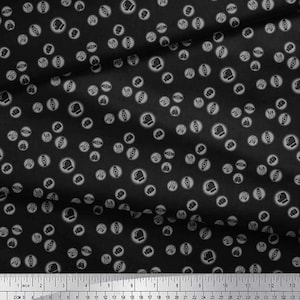 May include: Black fabric with a repeating pattern of boxing gloves and athletic shoes inside of white circles. The fabric has a wrinkled texture and a ruler is at the bottom of the image, measuring in inches.