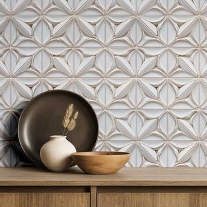 May include: A decorative display featuring a brown ceramic plate, a small white vase with dried grass, and a wooden bowl. The background showcases a white, patterned tile wall. The items are arranged on a wooden surface.