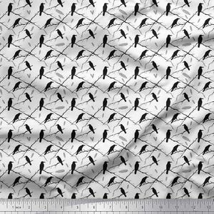May include: A fabric with a repeating pattern of black crows perched on bare branches against a white background. The design includes small gray feathers and hearts, creating a gothic or Halloween theme. The ruler at the bottom measures up to 13 inches.