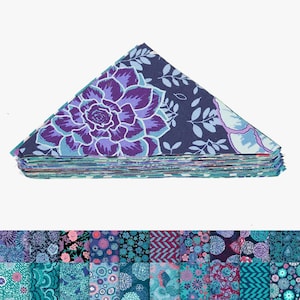 May include: A stack of pre-cut fabric squares with floral patterns. The top layer displays a large purple and blue succulent design on a navy background. Additional fabric squares with diverse floral and geometric prints are visible below.