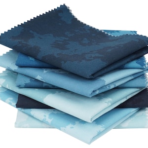 Peut inclure: Une pile d'échantillons de tissu dans différentes nuances de bleu, du clair au foncé. Chaque échantillon présente un motif unique ressemblant à une carte ou à une formation nuageuse. Les bords sont coupés en zigzag.