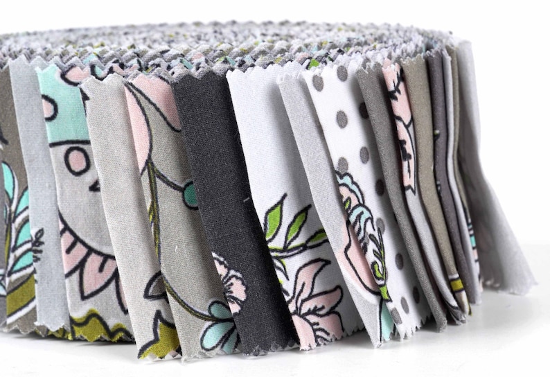 May include: A roll of fabric scraps in various shades of gray, white, and pink with floral and polka dot patterns.