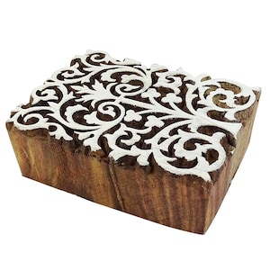 May include: A wooden printing block featuring a white intricate floral design. The block is rectangular and has a brown wood grain.