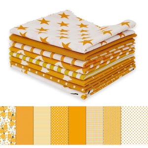 May include: A stack of folded fabric squares in various patterns and shades of yellow and white. Designs include stars, stripes, dots, and floral motifs. The fabric appears to be cotton or a similar material, suitable for quilting or crafting projects.