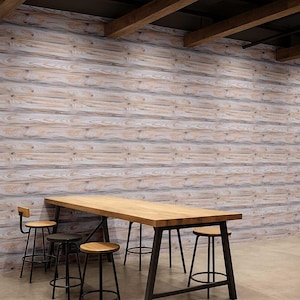 Puede incluir: Una mesa larga de madera con estructura metálica oscura y varios taburetes de madera. La mesa está frente a una pared hecha de tablones de madera de color claro. Los taburetes tienen patas de metal negro y asientos de madera.
