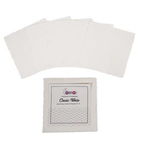 Puede incluir: Un conjunto de cuadrados de tela blanca con bordes festoneados, dispuestos sobre un fondo blanco. Los cuadrados van acompañados de un paquete etiquetado "Classic White", con texto que indica 100% algodón de primera calidad y dimensiones de 12,7 x 12,7 cm.