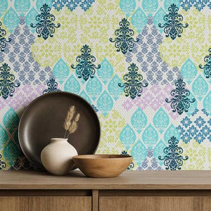 May include: A decorative arrangement featuring a brown ceramic plate, a small white vase with dried grass, and a wooden bowl on a wooden surface. The backdrop is a patterned wallpaper with teal, blue, and lavender floral designs.