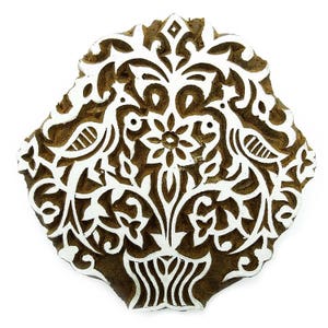 Könnte beinhalten: Ein brauner Holzblock-Stempel mit einem weißen Design aus zwei Vögeln, einer Blume und komplizierten floralen Mustern.
