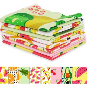 May include: A stack of colorful kitchen towels with fruit patterns. The towels feature designs of kiwi, watermelon, oranges, and other fruits in bright colors. The towels are folded and stacked neatly, showcasing the variety of patterns.