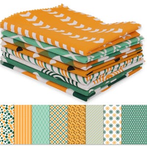 May include: A stack of patterned fabric squares in various designs and colours. The top fabric is orange with white chevron patterns. Other fabrics feature geometric and floral designs in green, white, and orange. The bottom of the image shows the fabric patterns.