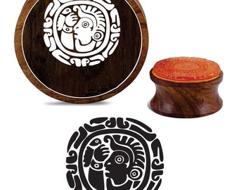 May include: A wooden stamp with a circular design featuring a stylized human face with geometric patterns. The stamp is mounted on a wooden base with a red rubber pad.