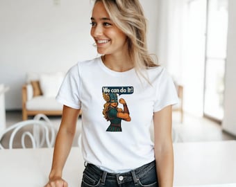 May include: White t-shirt featuring a cartoon illustration of a female superhero flexing her arm, with the text "We can do it!" in a speech bubble. The superhero is wearing a helmet and armor. The shirt is a classic crew neck.