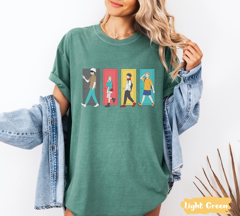 May include: Light green t-shirt featuring a graphic of four anime characters walking through colorful doors. The design includes characters in various outfits and poses. The shirt is a relaxed fit.