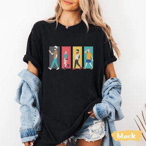 May include: Black t-shirt featuring a colorful graphic of four anime characters walking through doors. The doors are different colors: gray, red, yellow, and blue. The word "black" is printed in a yellow rectangle in the bottom right corner.