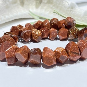 May include: A strand of brown and gold sunstone beads, each bead is faceted and has a rough, textured surface.