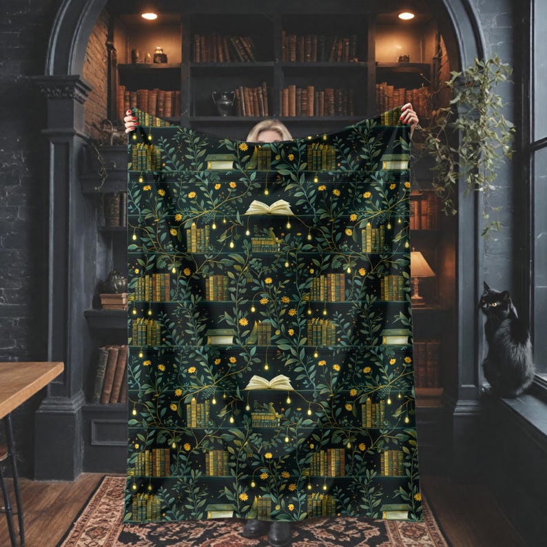 May include: A dark green blanket with a repeating pattern of books, vines, and yellow flowers. The blanket has a cozy, inviting aesthetic, perfect for a reading nook or library-themed decor. The design includes open books and string lights.