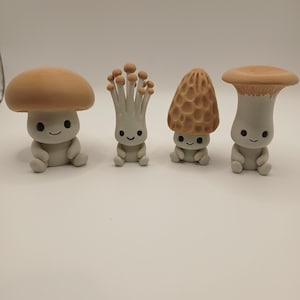 May include: Four whimsical mushroom figurines with smiling faces. Each mushroom has a different cap design, including a classic rounded cap, a cluster of small spheres, a textured cone, and a wide, flat cap. The figurines are primarily gray with brown or tan caps.