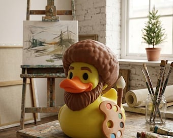 May include: A yellow rubber duck figurine styled with a brown afro hairstyle and a matching brown beard. The duck features an orange beak, black eyes, and holds a tan artist palette with colorful paint spots and a small paintbrush in its wing.