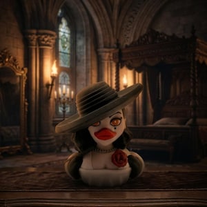 May include: A rubber duck figurine styled as a woman with dark hair, wearing a wide-brimmed hat, a pearl necklace, and a white dress with a red rose accent. The duck has orange eyes, a red beak, and a beauty mark on the left cheek.