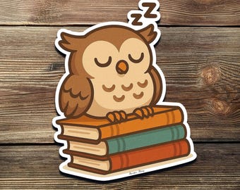 Puede incluir: Una pegatina con un búho de dibujos animados durmiendo sobre una pila de libros. El búho es marrón y beige con los ojos cerrados y una 'Zz' encima de la cabeza. Los libros son naranja, verde y rojo.