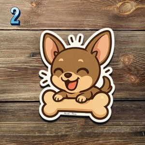 May include: A sticker of a cartoon chihuahua dog with a cheerful expression, holding a bone. The dog is brown with tan ears and a white outline. The number 2 is in blue in the upper left corner. The sticker is on a wooden background.