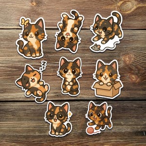 May include: A collection of eight cat stickers in various poses. The stickers feature cartoon-style calico cats with black, brown, and orange markings. One cat wears glasses, and another plays with a ball of yarn. The stickers are on a wooden background.