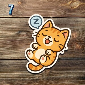 May include: A sticker featuring a cartoon orange cat sleeping with its eyes closed and tongue sticking out. A blue speech bubble with the letter "Z" is above the cat's head. The number "7" is in the upper left corner.