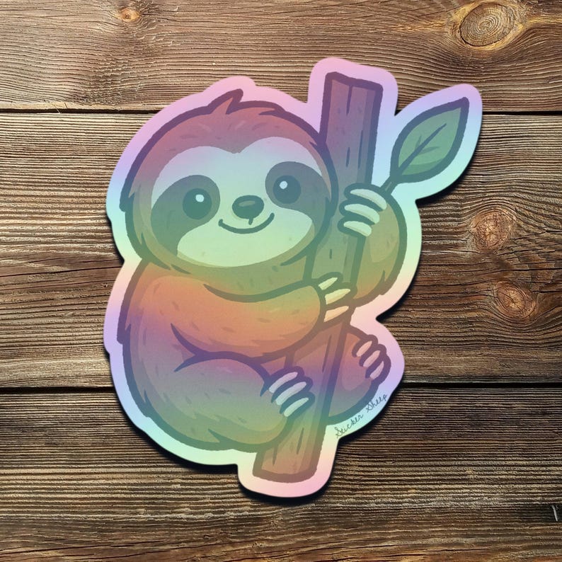 May include: A holographic sticker featuring a cartoon sloth clinging to a branch with a leaf. The sloth has a smiling face and is colored with a rainbow gradient. The sticker is on a wooden background.