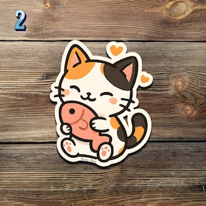 May include: A sticker featuring a cartoon calico cat hugging a pink fish. The cat has a white face with orange and black markings, a black tail, and orange hearts. The sticker is on a wooden surface.