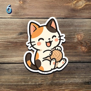 May include: A cartoon sticker of a happy calico cat holding a ball of yarn. The cat has orange, black, and white fur, with a smiling face and pink cheeks. The sticker is on a wooden background, with the number 6 in the upper left corner.