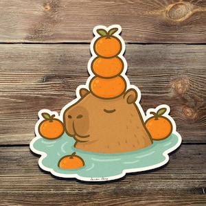 Peut inclure: Un capybara brun portant une pile de mandarines oranges sur la tête. Le capybara est dans une piscine d'eau avec d'autres mandarines autour de lui.