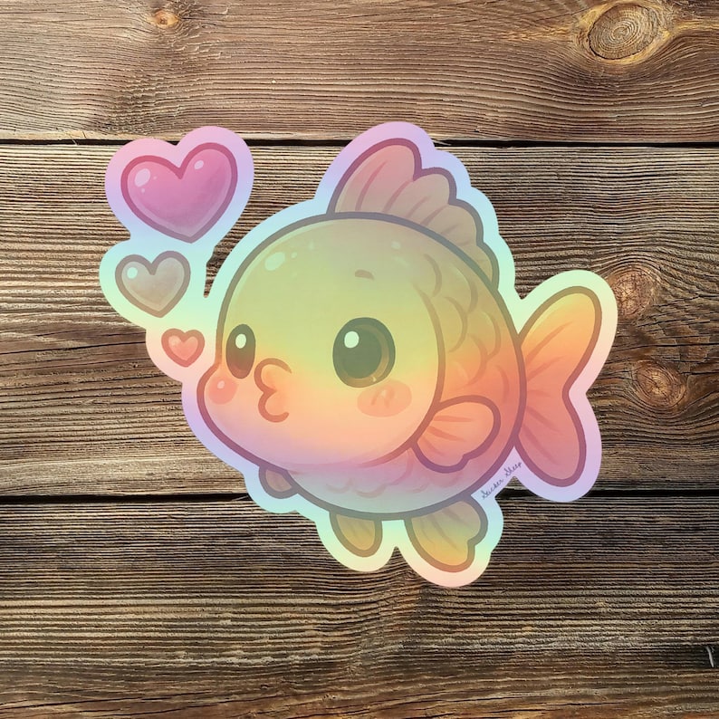 May include: A holographic sticker of a cartoon goldfish with a rainbow gradient. The fish has large eyes and is blowing kisses, with three pink hearts floating above it. The sticker is on a wooden background.