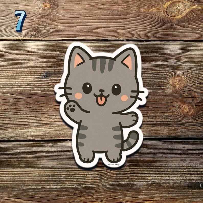 May include: A gray cartoon cat sticker with a white border. The cat has black eyes, pink cheeks, and a pink tongue sticking out. The cat is waving with its left paw. The number 7 is in the top left corner.