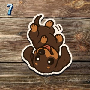 May include: A sticker of a cartoon dachshund dog, brown and tan, lying upside down with its tongue out. The sticker has a white outline. The number 7 is in the top left corner.