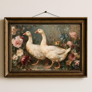 May include: A framed painting featuring two white geese with orange beaks and feet, set against a backdrop of colorful flowers. The artwork is in a gold-toned frame, creating a vintage aesthetic. The painting is hung on a white wall.
