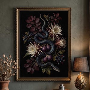 Op de afbeelding: Een ingelijst rechthoekig wandkunstwerk met een donkere botanische illustratie van een kronkelende zwarte slang omringd door witte nachtbloeiende bloemen, paarse vijgen en donkere bessen tegen een zwarte achtergrond in een goudkleurige lijst.