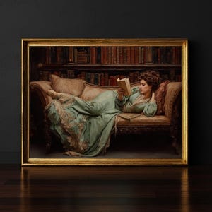 May include: A framed print of a woman in a flowing green dress reading a book while reclining on a chaise lounge. The lounge is brown with decorative carvings. A bookshelf filled with books is in the background. The frame is gold.