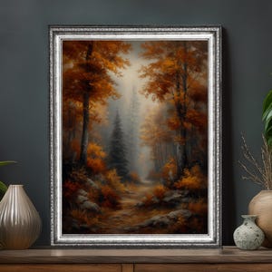 May include: A framed landscape painting depicts an autumn forest scene. The artwork features trees with vibrant orange and yellow foliage, a path leading into the distance, and a misty atmosphere. The frame is silver.