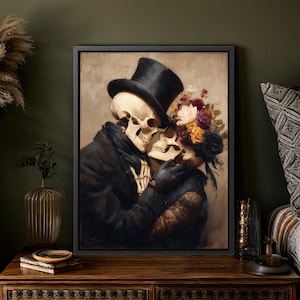 May include: A framed artwork depicts two skeletons embracing. One skeleton wears a black top hat and coat, the other is adorned with a floral crown. The painting has a vintage aesthetic with a dark color palette, creating a romantic and gothic theme.