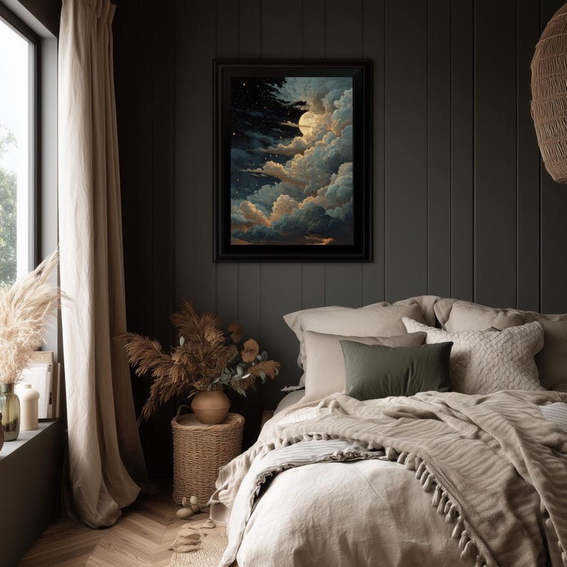 Op de afbeelding: Een ingelijst kunstwerk dat een nachtelijke hemel met een volle maan, wolken en sterren afbeeldt. Het kunstwerk hangt boven een bed met beige beddengoed en kussens. De kamer heeft donkergrijze muren, een raam met beige gordijnen en een bijzettafel van gevlochten mand.