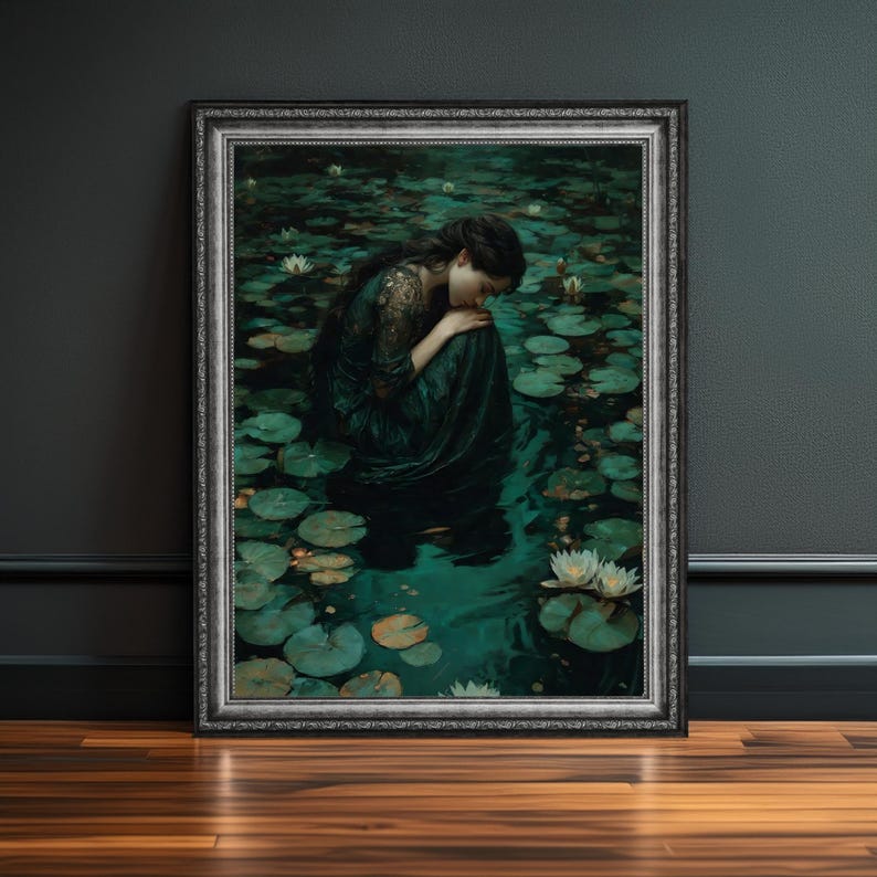 May include: A framed art print depicts a woman in a dark green dress seated among lily pads in a pond. The artwork has a vintage aesthetic, with a silver frame and a dark, moody color palette. White water lilies dot the water's surface.