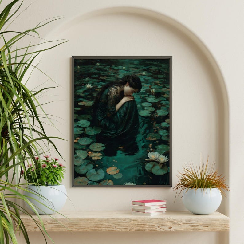 May include: Framed art print featuring a woman in a dark green dress, seated amidst lily pads in a pond. The artwork has a vintage aesthetic, with a muted color palette of greens and blues. The woman is the focal point, with her head bowed.