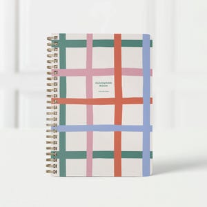 May include: A spiral-bound password book with a colorful grid pattern. The cover features a white background with intersecting lines in teal, pink, orange, and blue. The text "PASSWORD BOOK" is printed in black.