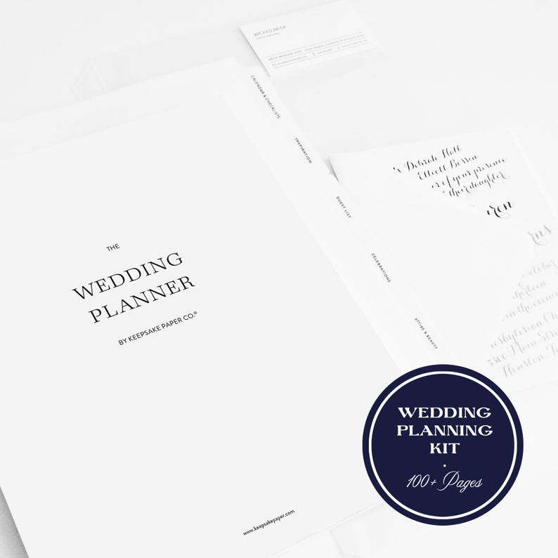 K&ouml;nnte beinhalten: Ein wei&szlig;es Hochzeitsplaner-Set mit dem Text "The Wedding Planner" und "By Keepsake Paper Co." in Schwarz gedruckt. Ein marineblauer Kreis mit dem Text "Wedding Planning Kit" und "100+ Pages" ist ebenfalls sichtbar.