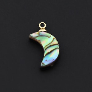 May include: A crescent-shaped pendant with iridescent abalone shell inlay. The pendant has a gold-colored loop at the top for hanging. The shell displays a mix of green, blue, and gold colors. The background is a solid black.