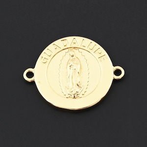 May include: A gold-colored Guadalupe pendant with a circular design. The pendant features an image of the Virgin Mary in the center, surrounded by the word "GUADALUPE". Two small loops are on either side of the pendant.