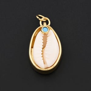 May include: A gold-colored pendant with an oval frame, featuring a natural seashell. A small, round, turquoise-colored stone is set at the top. The pendant hangs from a small loop.