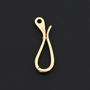 Puede incluir: Un cierre de langosta dorado con forma de lágrima y un pequeño agujero en la parte superior. El cierre está diseñado para conectar dos partes de un collar o pulsera. El fondo es negro liso.