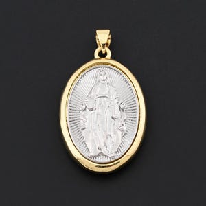 May include: Oval pendant with a gold-colored frame and bail, featuring a silver-colored image of a religious figure. The figure is depicted with outstretched arms, set against a textured background. The pendant is suspended against a black background.